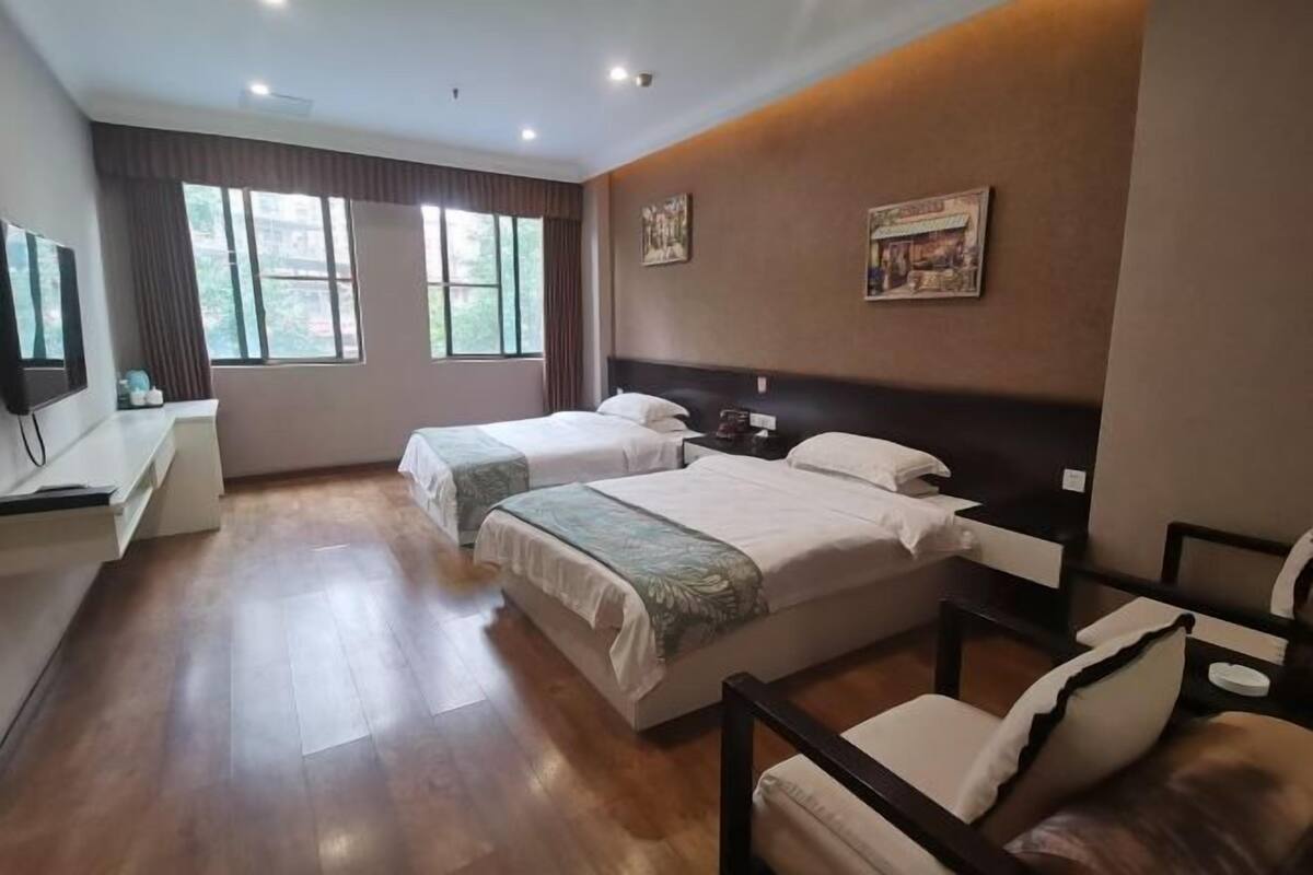 A hotel room with two beds, a desk, and a chair.