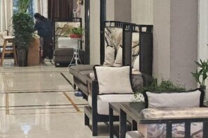 A hotel lobby with a seating area, a small table, and a potted plant.