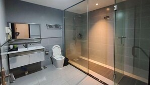 A modern bathroom with a glass shower enclosure, a toilet, and a vanity with a mirror. - Linlong Hotel in Yinjiang (Yinjiang)