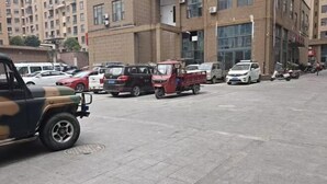 A parking lot with various vehicles including cars and a red three-wheeled vehicle. - Linlong Hotel in Yinjiang (Yinjiang)