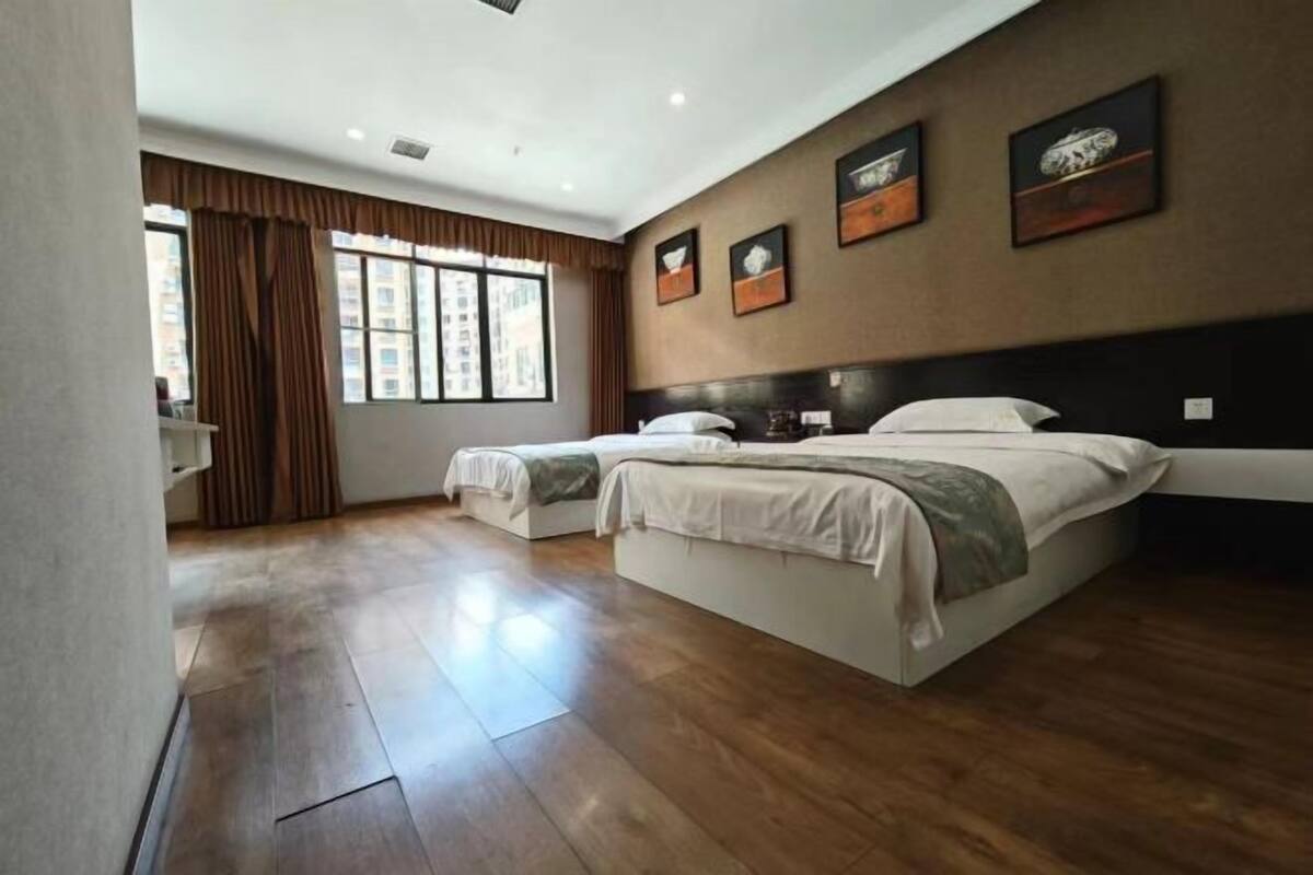 A hotel room with a large bed, a bedside table, a window with curtains, and artwork on the wall.