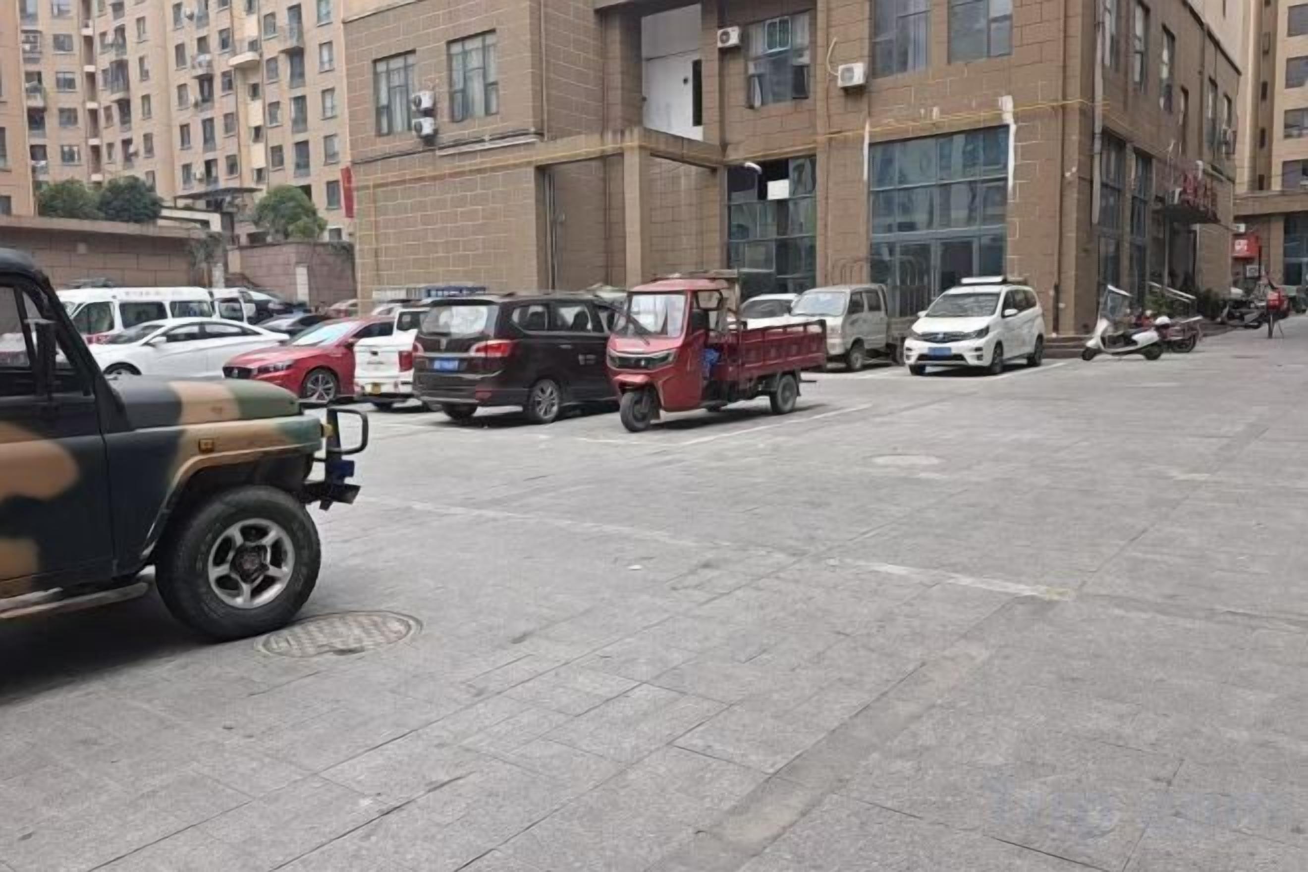 A parking lot with various vehicles, including a red pickup truck and a white car.
