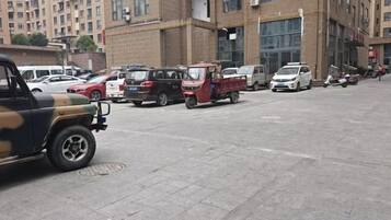 A parking lot with various vehicles, including a red pickup truck and a white car.