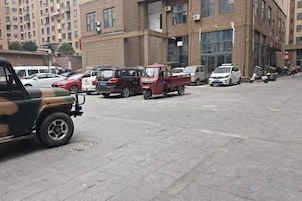 Un estacionamiento con varios vehículos, incluyendo una camioneta roja y un coche blanco.