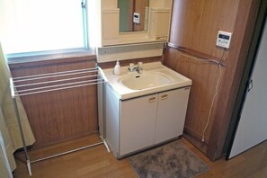 A compact bathroom with a white sink, a mirror above it, and a towel rack. - Nodoka (Nikko)