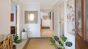 A hallway with a wooden floor, a glass door on the right, and a mirror on the left. - Gillmith - Up to 10 people (Pambula Beach)
