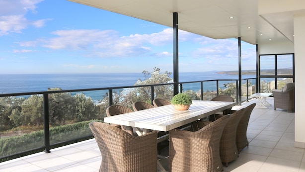 A balcony with a view of the sea, wicker furniture, and a potted plant. - Villa Paradiso - Pool and Beach Front (Tura Beach)