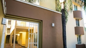 A building entrance with a gated door, a staircase leading to an upper level, and a palm tree.