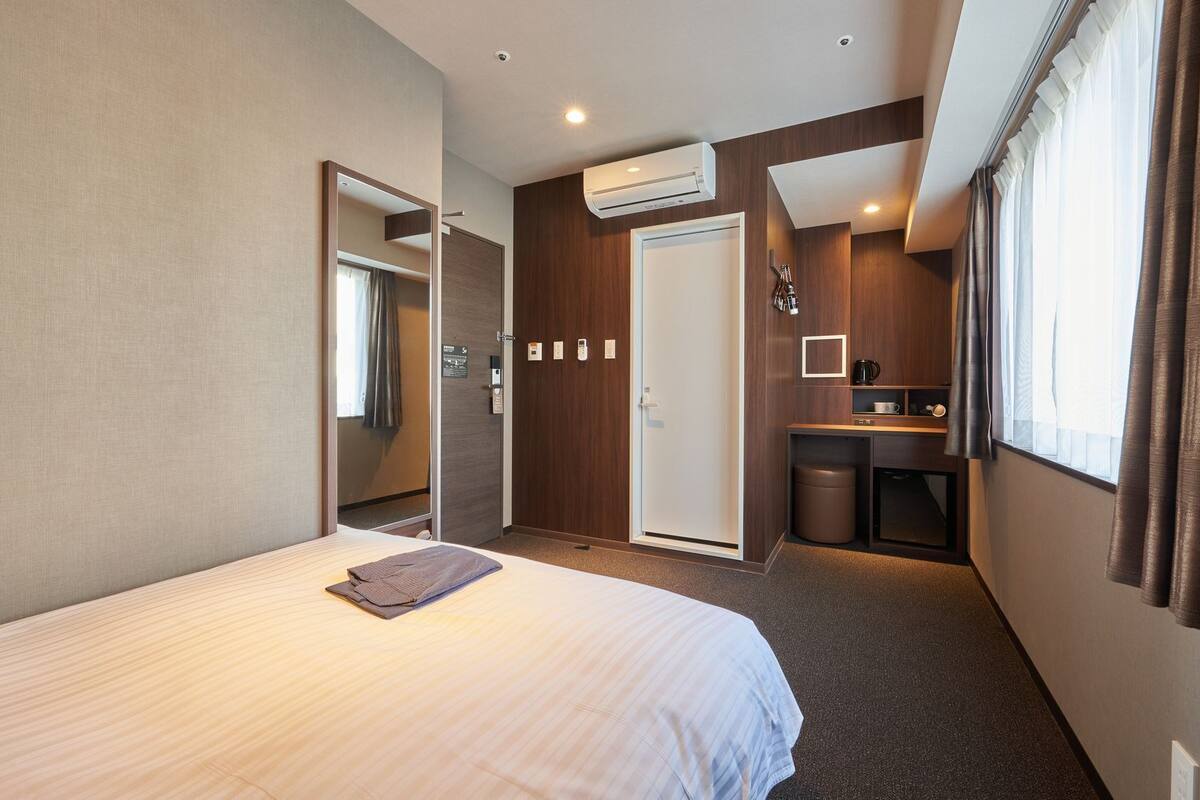 Una habitación de hotel con cama, kitchenette pequeña, baño y espejo.