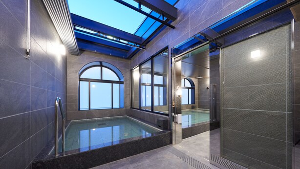 Una piscina interior moderna con tragaluces, ventanas amplias y una puerta de cristal que da a otra zona.