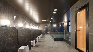 Un baño moderno con varios lavamanos, una zona de piscina y una puerta de madera.