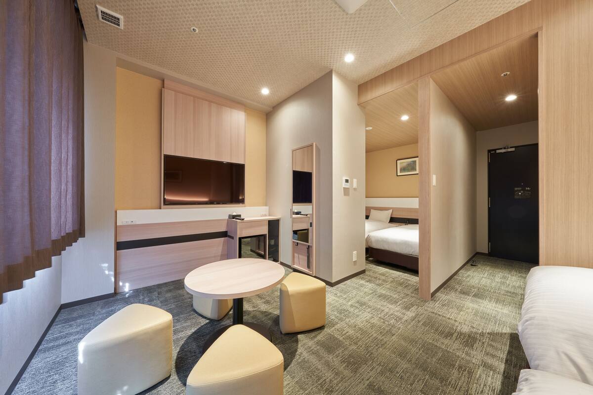 Una habitación de hotel moderna con kitchenette, una cama, un escritorio y una zona de estar.