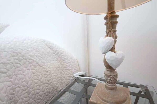 A bedside table with a lamp featuring a decorative base and heart-shaped lampshades.