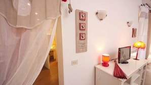 A room with a white console table, a red lamp, and a wall-mounted shelf.