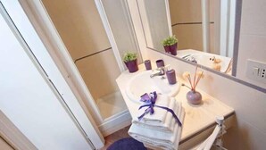 A bathroom with a sink, mirror, and two potted plants.