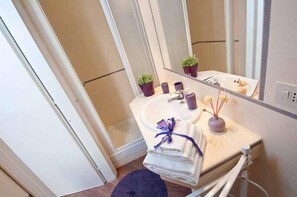 Casa de banho com lavatório, espelho e duas plantas em vasos.