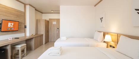 Habitación de hotel con dos camas, un escritorio, un televisor y una puerta.