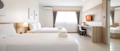 A hotel room with two beds, a desk, a chair, and a TV on the wall.