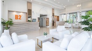 A modern hotel lobby with white furniture, a reception desk labeled 'B2', and large windows. - B2 Phitsanulok Boutique & Budget Hotel (Phitsanulok)