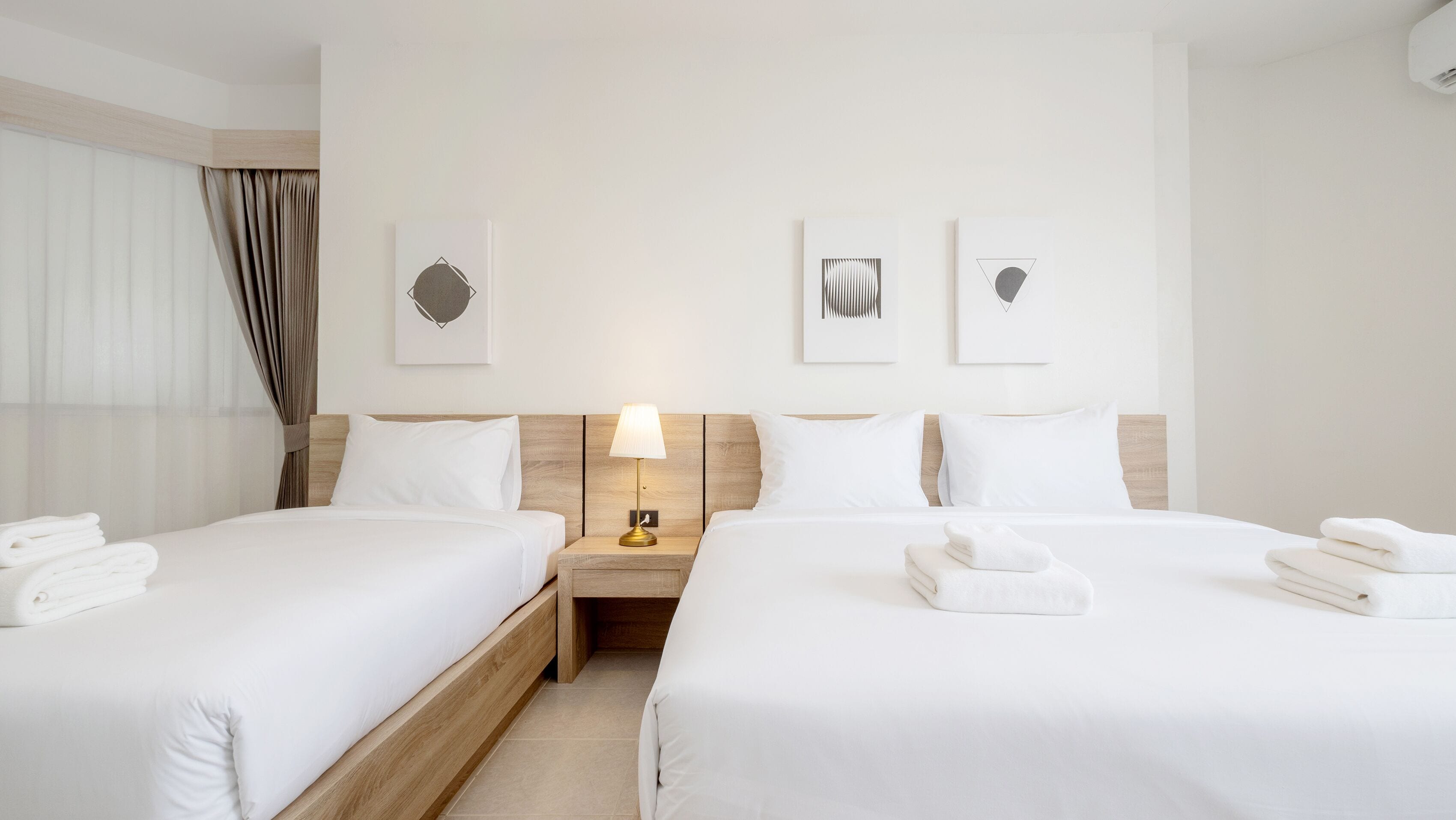 Une chambre d’hôtel avec deux lits, une table de chevet avec une lampe et des œuvres d’art accrochées au mur.