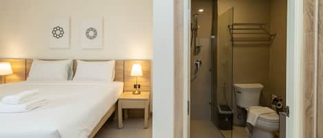 Una habitación de hotel con cama, lámparas de noche, ducha y retrete.