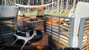 A cozy outdoor seating area with a hammock, a table with a mug, and a wooden chair. - Luxury Angel Fire Retreat - Fireplace, Skiing & Mountain Charm (Angel Fire)