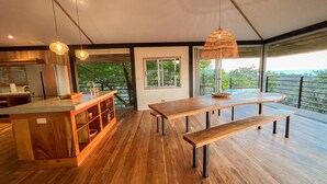 Una cucina moderna con isola in legno, zona pranzo con panche e un'ampia finestra vista verde.
