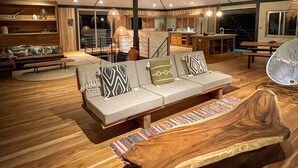 Un'ampia zona giorno con pavimento in legno, un divano spazioso con cuscini decorati, un tavolino in legno e una ventola a soffitto.
