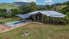 A modern house with a swimming pool, surrounded by lush greenery and hills.