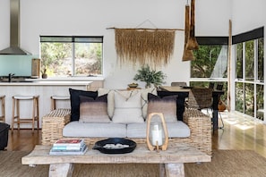 A modern living room with a sofa, coffee table, and a hanging decorative piece.