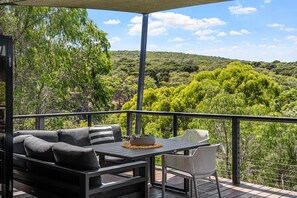 A balcony with a table and chairs, overlooking a lush landscape.