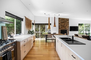 A modern kitchen with a large island, wooden cabinets, and a stone accent wall.
