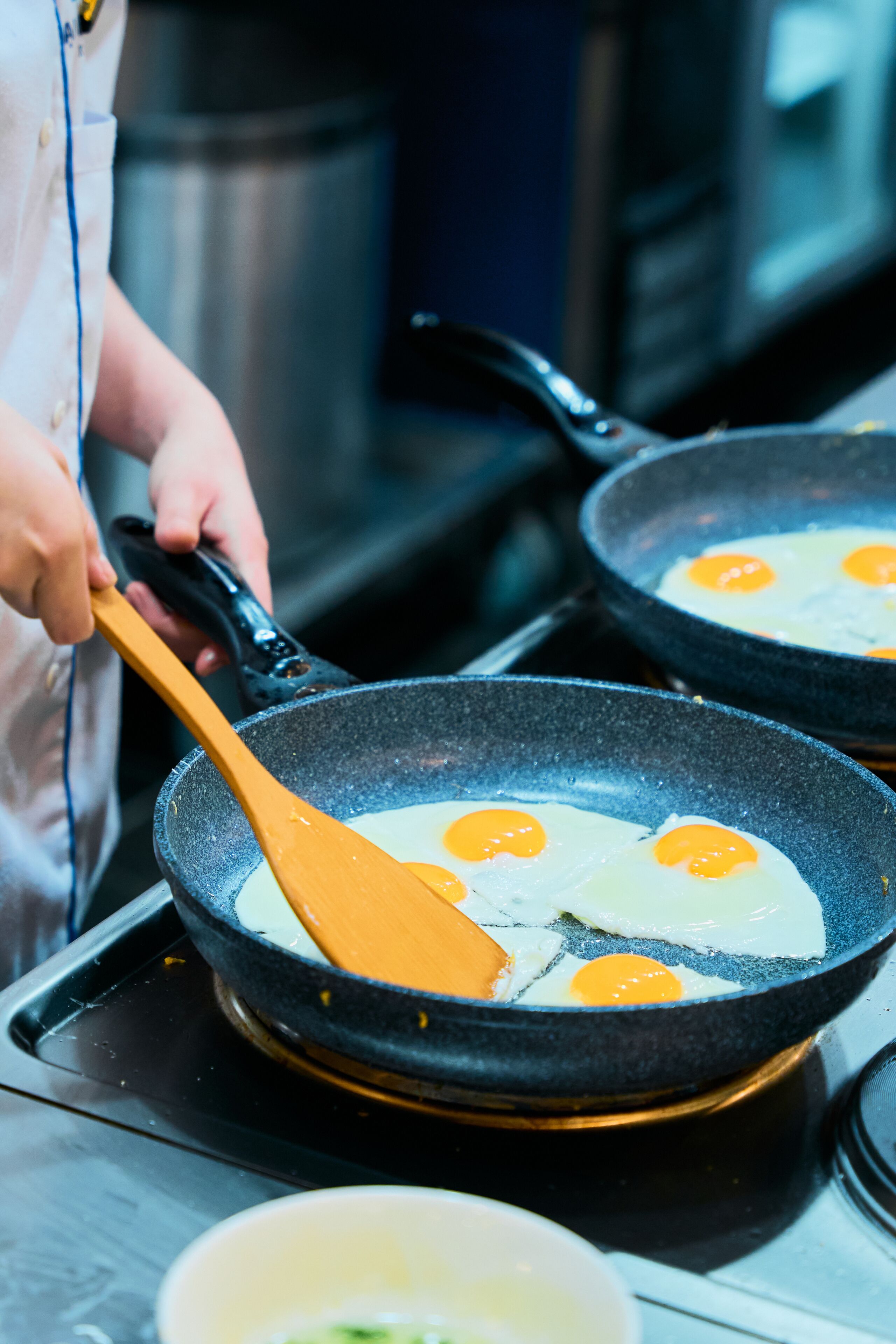 A person cooking eggs in a pan on a stove.