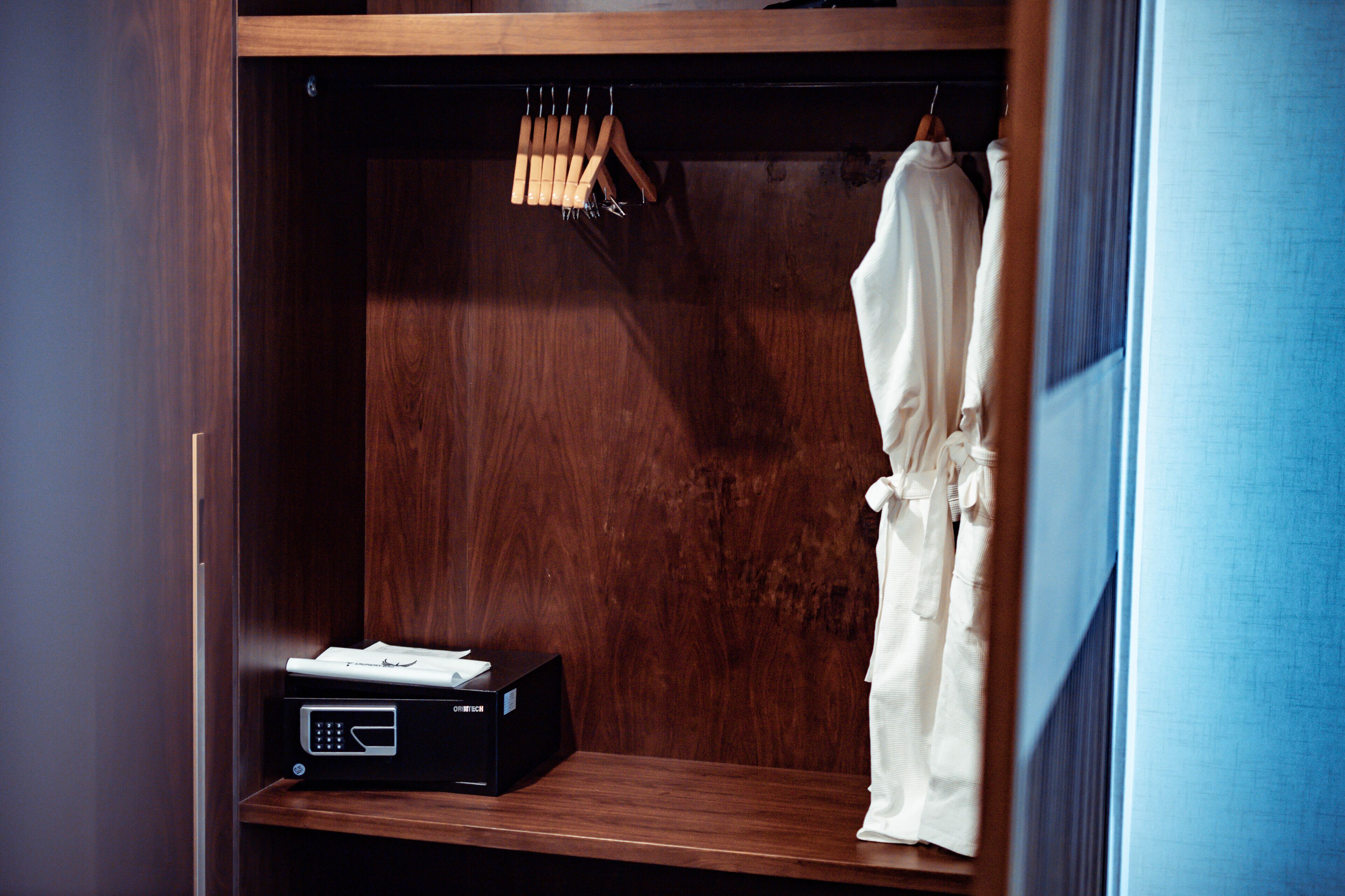 A wooden wardrobe with a shelf, a hanging rack, and a white robe.