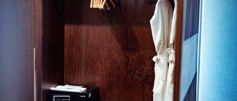 A wooden wardrobe with a shelf, a hanging rack, and a white robe.