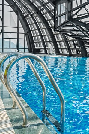 Swim laps in the pool surrounded by a modern glass enclosure.