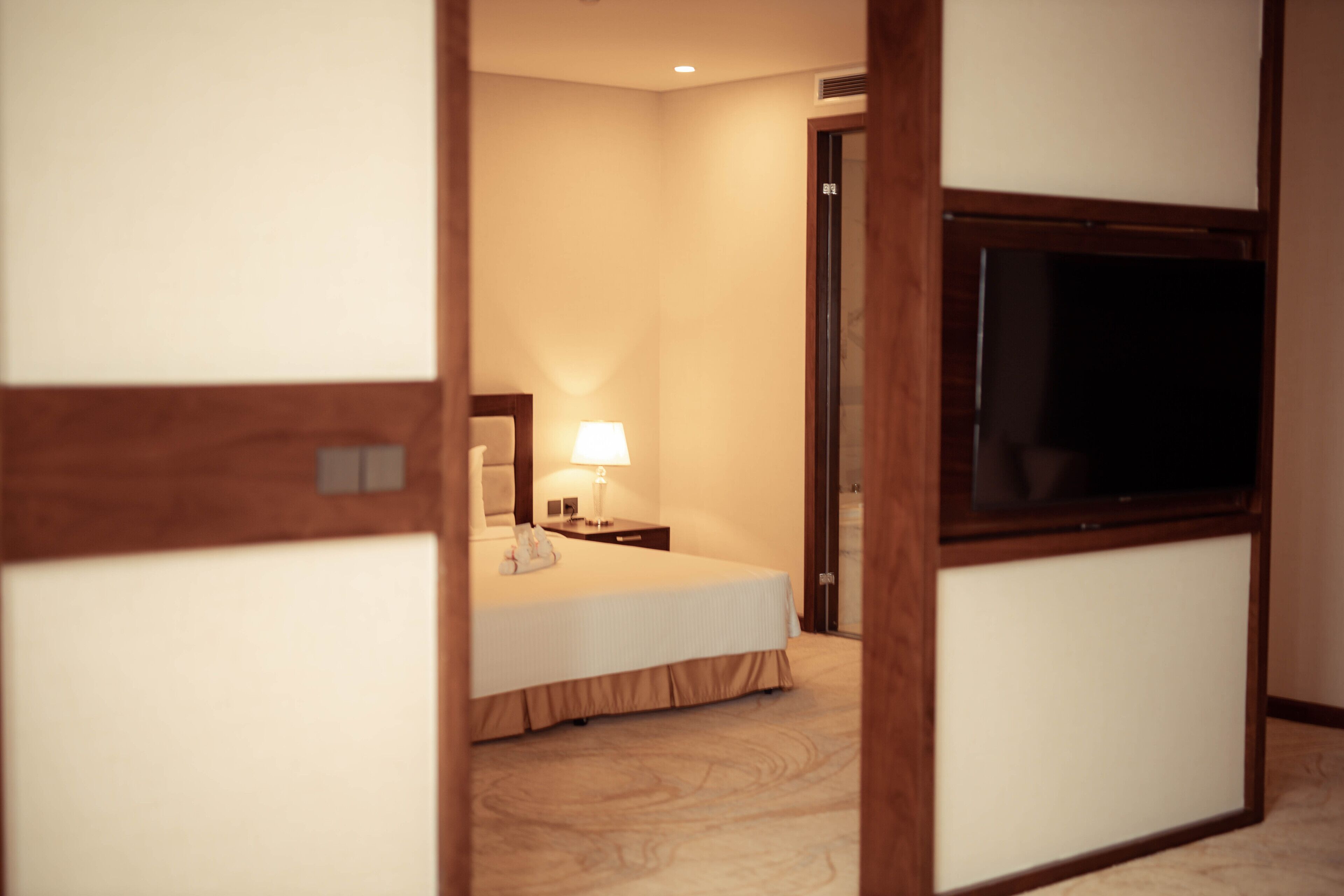 Une chambre d’hôtel avec un lit, une table de chevet, une lampe et un téléviseur posé sur un meuble.