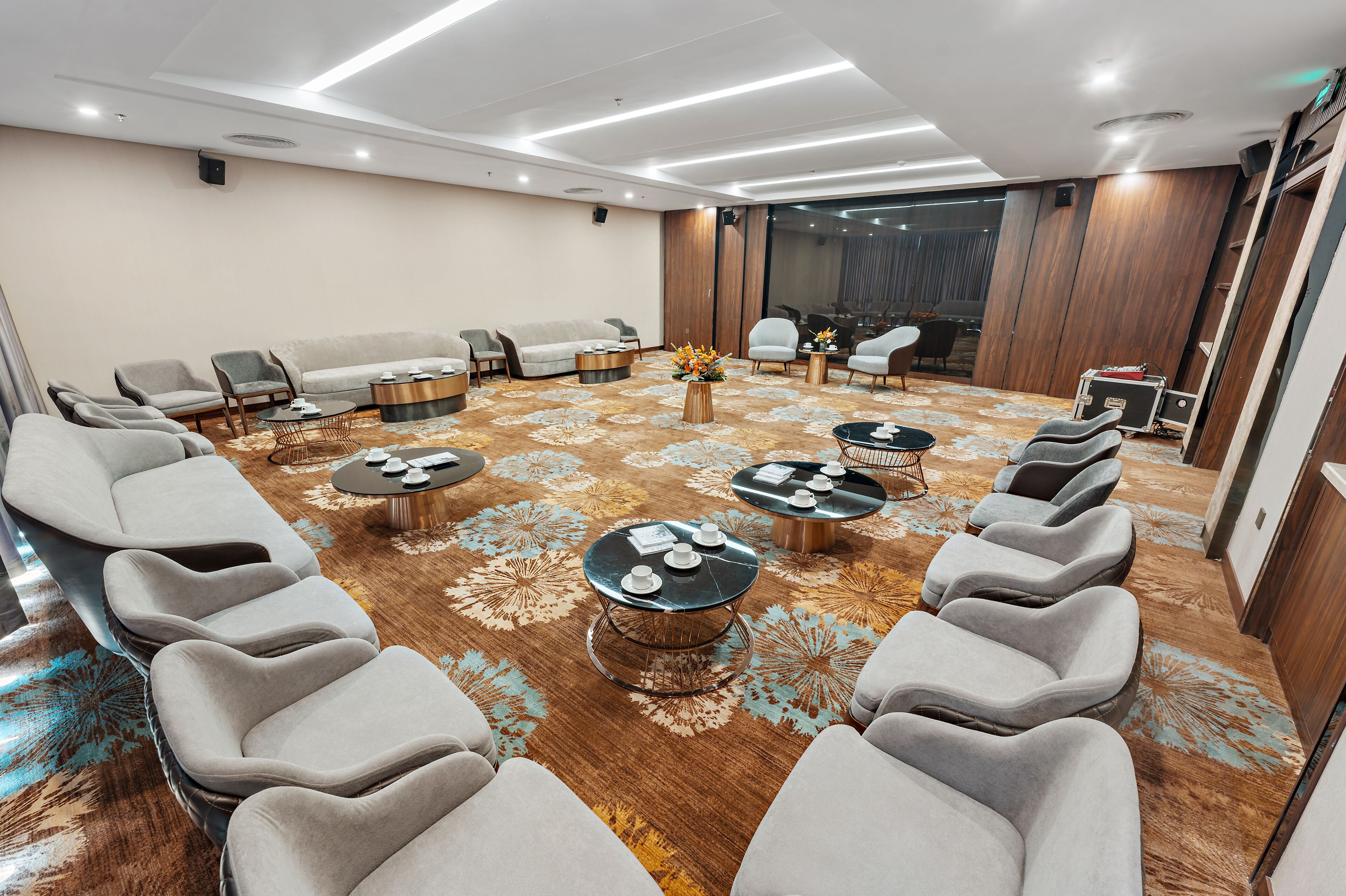 Une chambre d’hôtel moderne, dotée d’une rangée de fauteuils de massage, d’un canapé et d’une petite table sur laquelle est posé un vase de fleurs.
