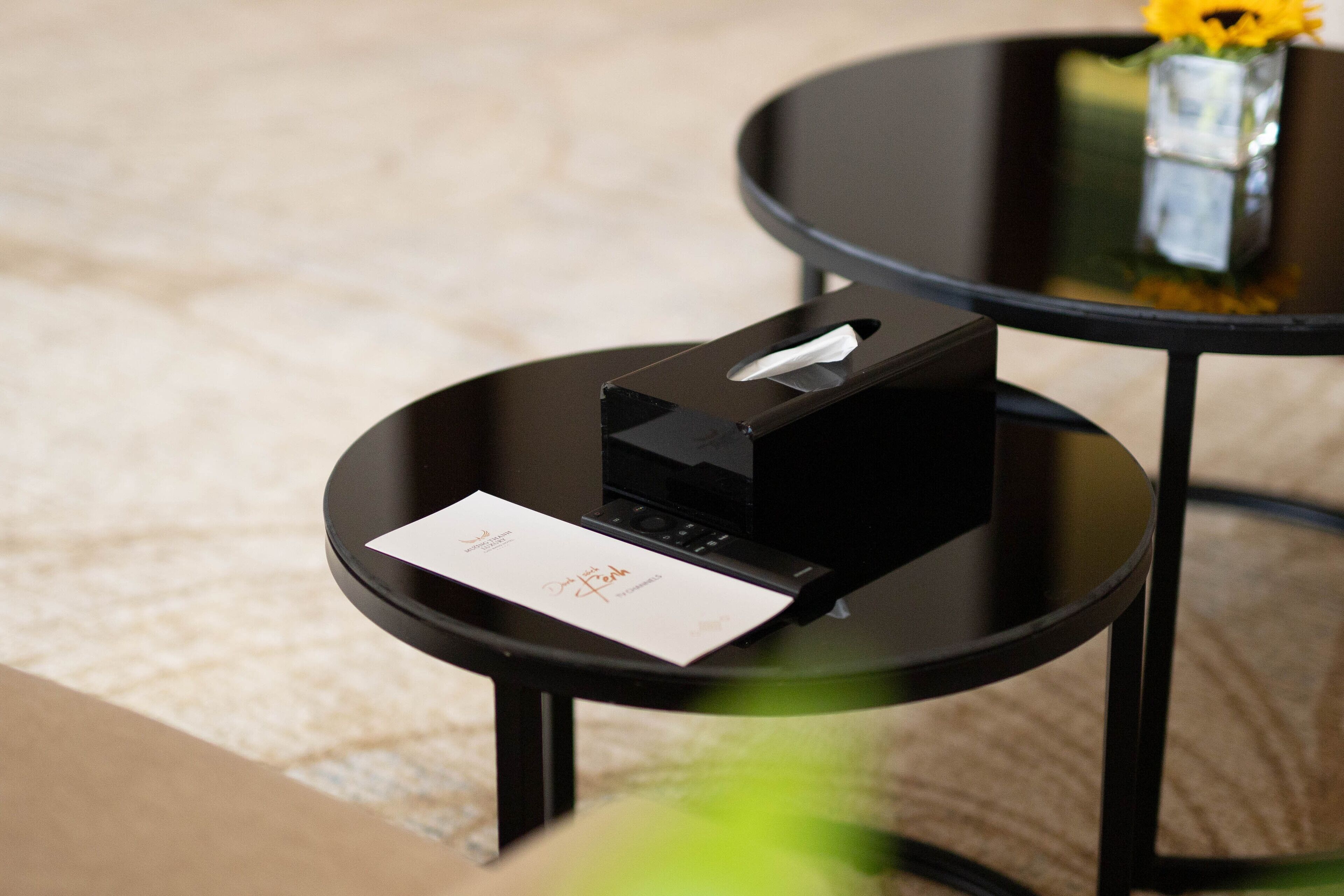 Une table noire sur laquelle se trouvent une boîte de mouchoirs et une carte de visite.