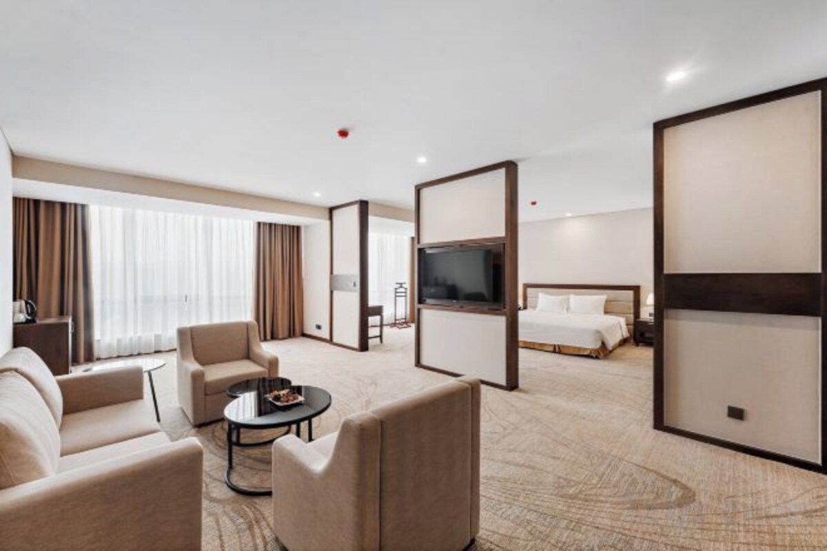 A hotel room with a bed, a TV, a sofa, and a coffee table.
