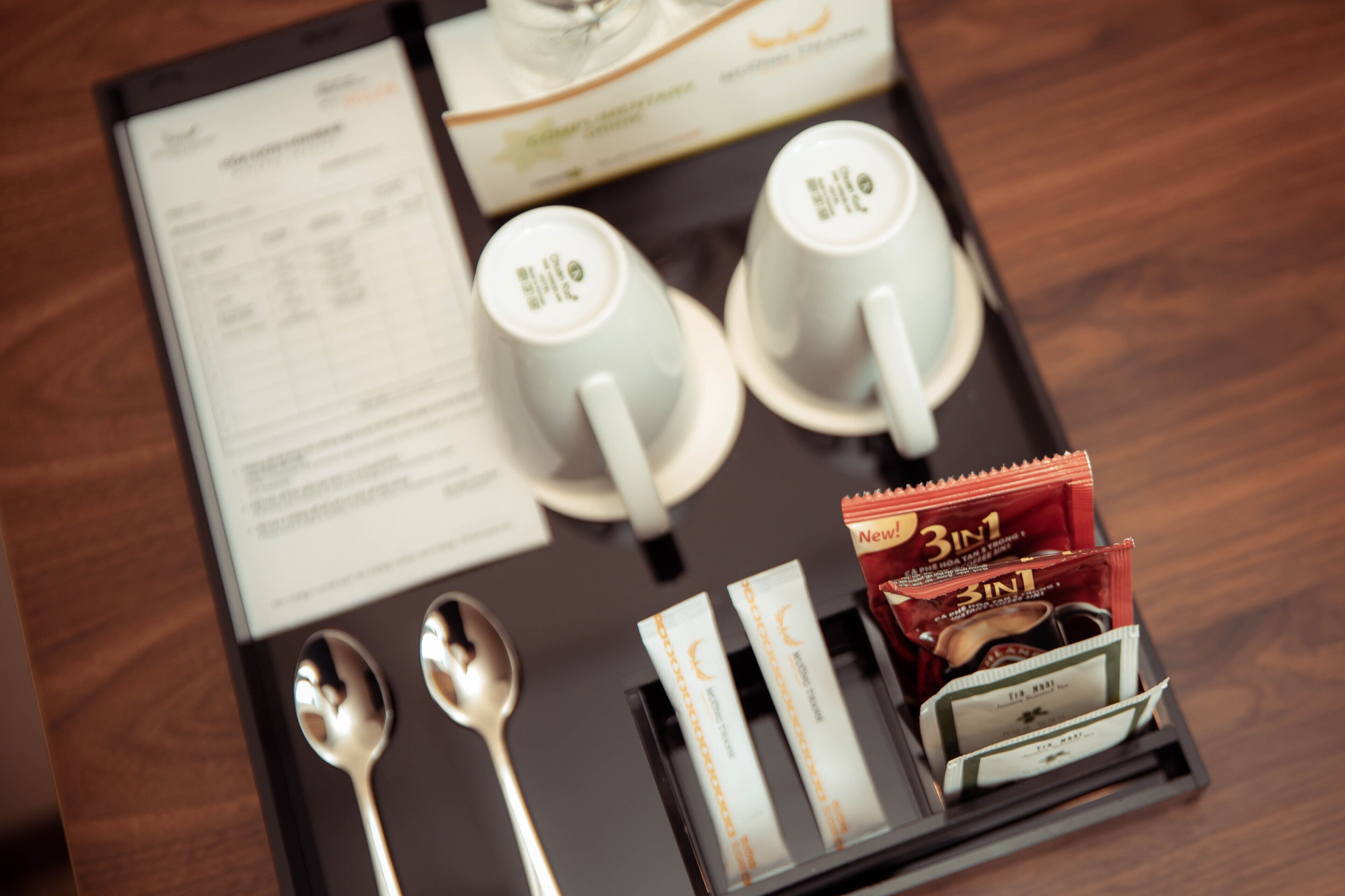 Un plateau avec deux tasses, deux cuillères et une boîte de sachets de thé.