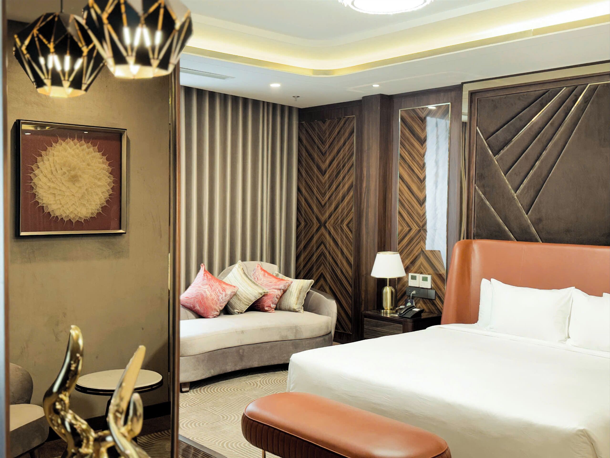 A hotel room with a large bed, a sofa, a small table, and a lamp.