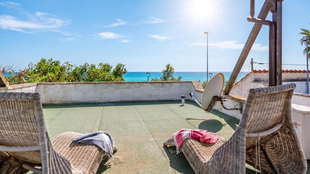 Eine Dachterrasse mit Korbstühlen, einer Satellitenschüssel und Blick auf den Ozean.