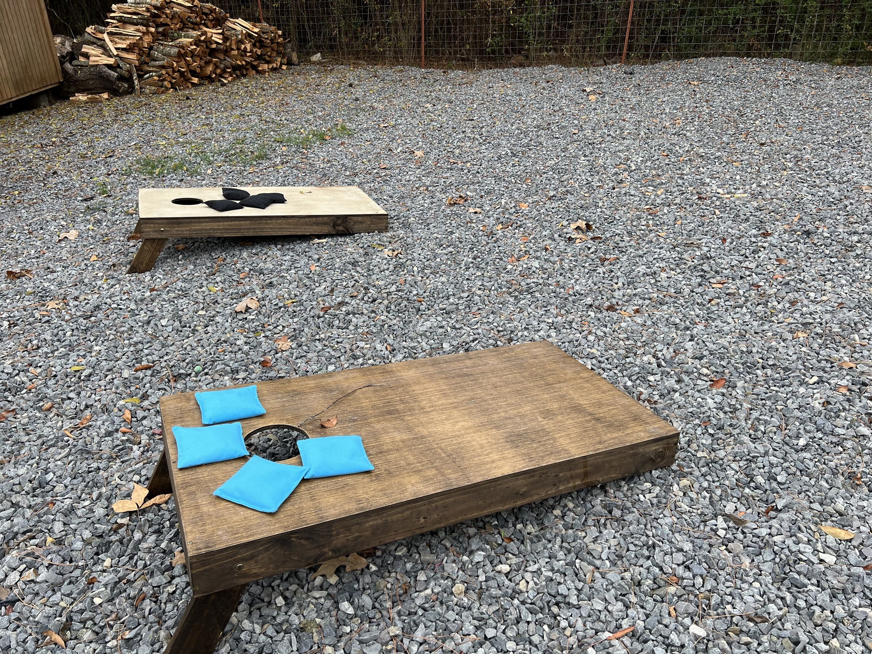 Two wooden boards on a gravel surface, one with black shapes and the other with blue shapes.