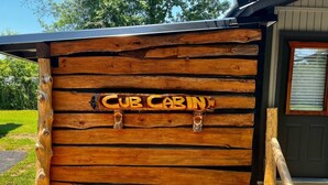 Eine Holzhütte, deren Vorderwand mit dem Schriftzug 'Cub Cabin' versehen ist.