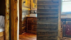 Ein rustikaler Holzraum mit einer Steinwand, einer hölzernen Sitzbank und einer kleinen Spüle.