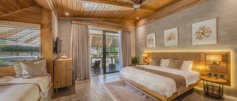 A spacious bedroom with a large bed, a smaller bed, a ceiling fan, and a view of the outdoors.