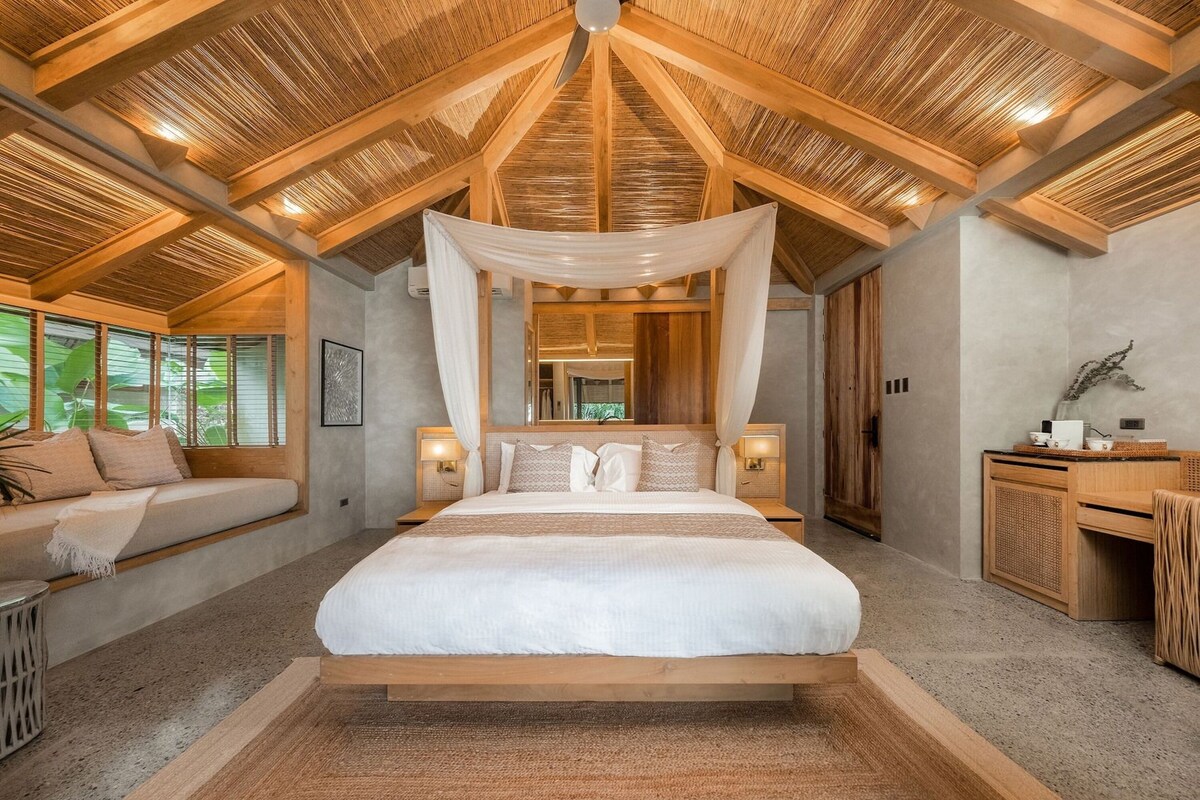 Une chambre à coucher avec un grand lit, des poutres apparentes en bois au plafond et un baldaquin.