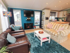 A living room with a brown leather sofa, a striped sofa, a white coffee table, and a fireplace. - Rosie's Zen Den (Carlisle)