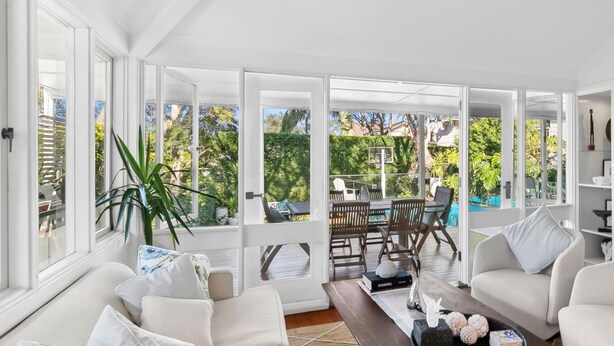 A spacious living room with a large window, a dining area, and a pool view.